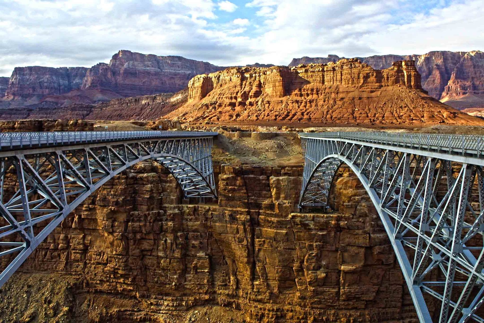 Twin steel arch bridges crossing a red-rock canyon, photographed by Bill Bell